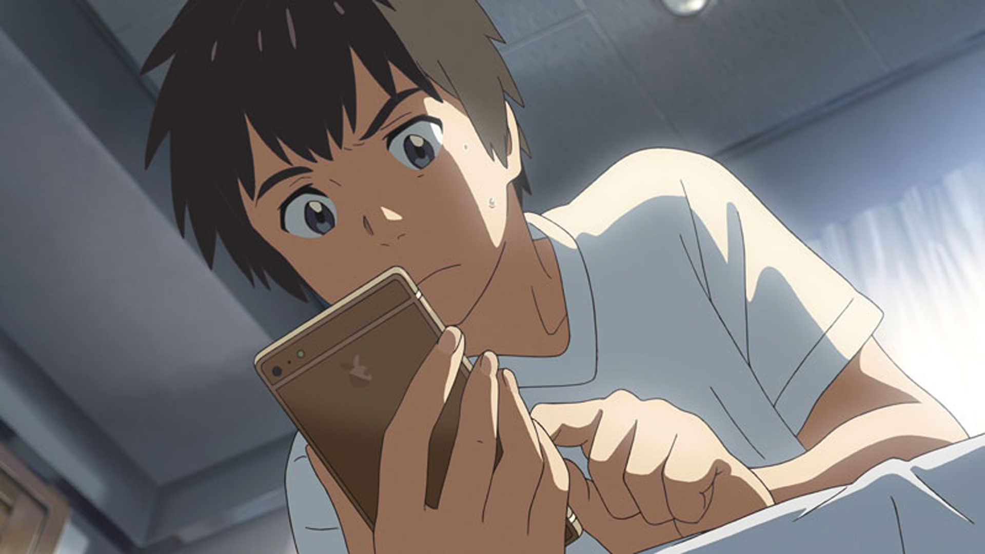 YOUR NAME – GESTERN, HEUTE UND FÜR IMMER: Der junge Taki schaut auf sein Mobiltelefon.