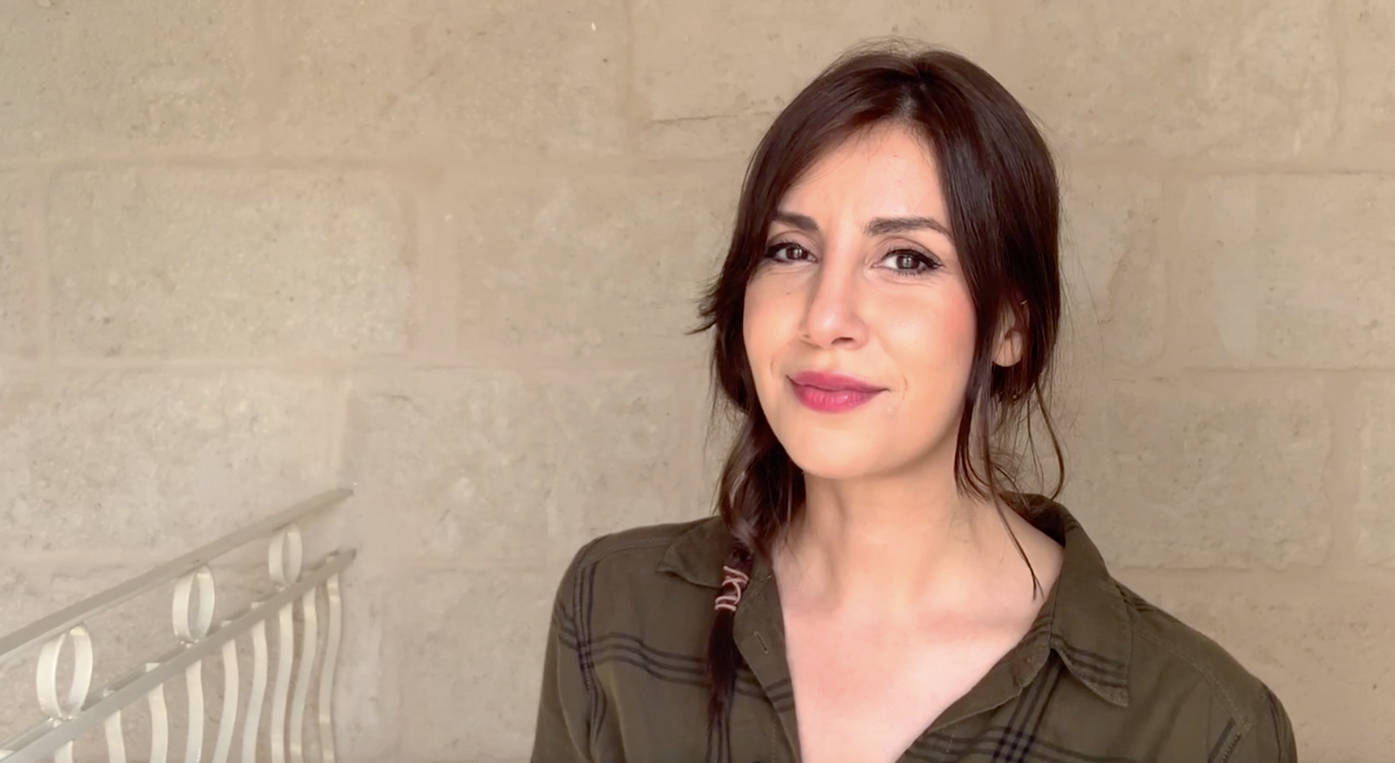 Sou Boujloud steht vor einer braunen Wand und weist auf das Thema ihrer Kolumne hin: Trailer.